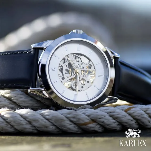 Karlex-klocka i stål med skelettad urtavla och svart läderarmband, liggande på ett tjockt tåg