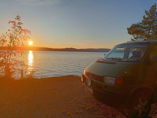 Bussen Mossa parkerad vid en sjö i solnedgången